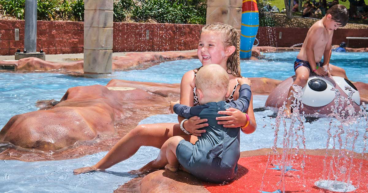 Girl holding baby in the splash pool at the Murwillumbah Centre